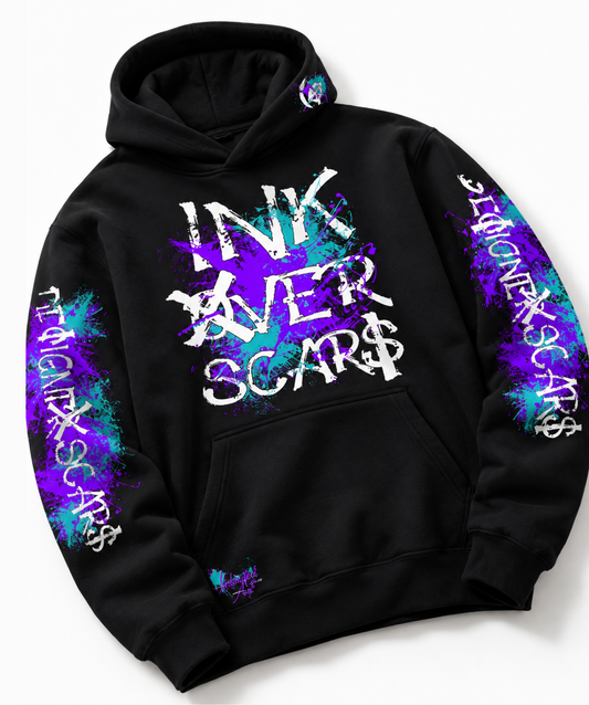 A black pullover hoodie with a front kangaroo pocket, featuring a large distressed white graphic on the chest that reads 'INK OVER SCAR$' over a purple and blue paint splatter design. The sleeves also feature vertical white text reading 'INK OVER SCAR$' integrated with matching purple and blue splatters.